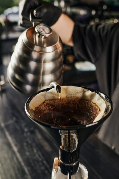 Barista pouring boiling water into paper filter of siphon coffee maker while brewing fresh espresso — Stock Photo
