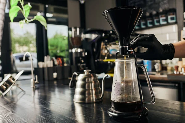 Parcial, barista regulador sifão cafeteira perto de chaleira gotejamento metálico no café moderno — Fotografia de Stock