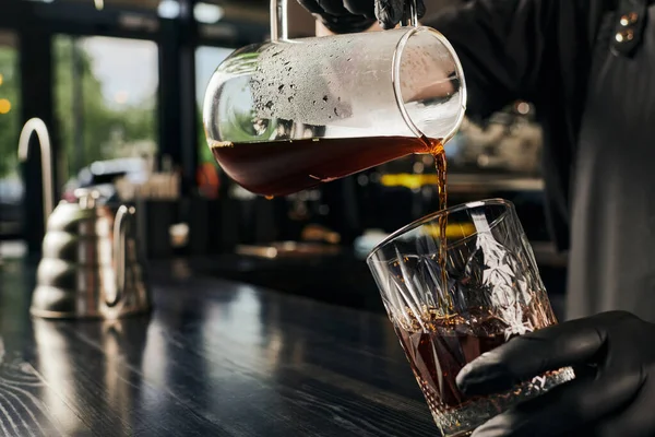Teilansicht des Barista, der im Coffeeshop aromatischen Espresso aus der Kaffeekanne in Kristallglas gießt — Stockfoto