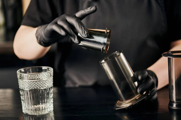 Vista cortada de barista em luvas de látex preto derramando café moído em aero imprensa perto de vidro de cristal — Fotografia de Stock