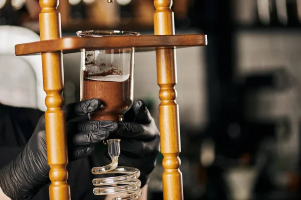 Barista in black latex gloves assembling parts of cold drip coffee maker, alternative coffee brewing — Stock Photo