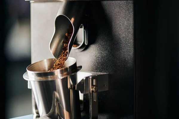 Équipement de café, café moulu versant du moulin à café électrique dans la tasse métallique de mesure — Photo de stock