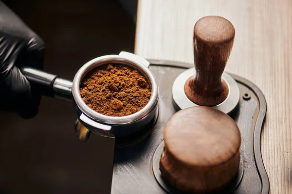 Barista holding portafilter with grinded coffee, tamper, cafe, alternative brew, top view — стоковое фото