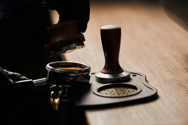 Cropped view of barista holding tamper near portafilter with grinded coffee, espresso, professional — Stock Photo