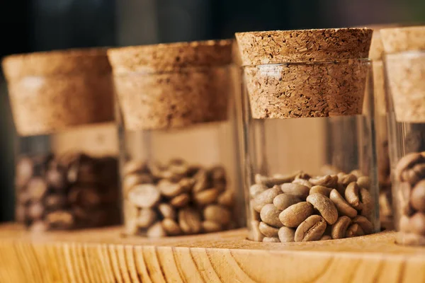 Grains de café bruns dans des bocaux en verre avec liège, torréfié, caféine et énergie, fond de café, flou — Photo de stock