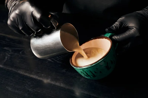 Parcial, barista em luvas de látex preparar cappuccino, café expresso, arte latte, jarro com leite — Fotografia de Stock
