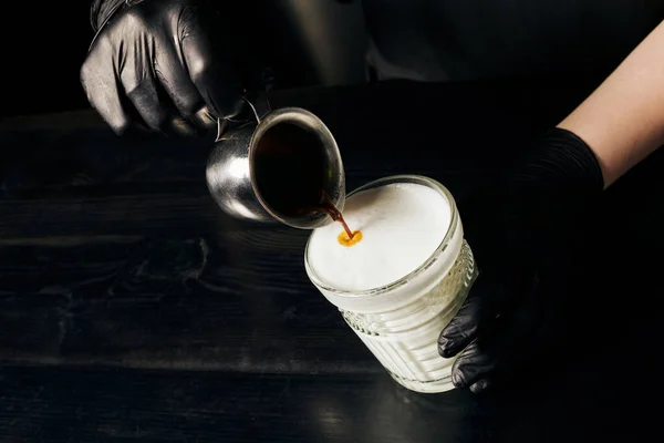 Barista in latex gloves preparing latte macchiato, pouring espresso, pitcher with black coffee — Stock Photo