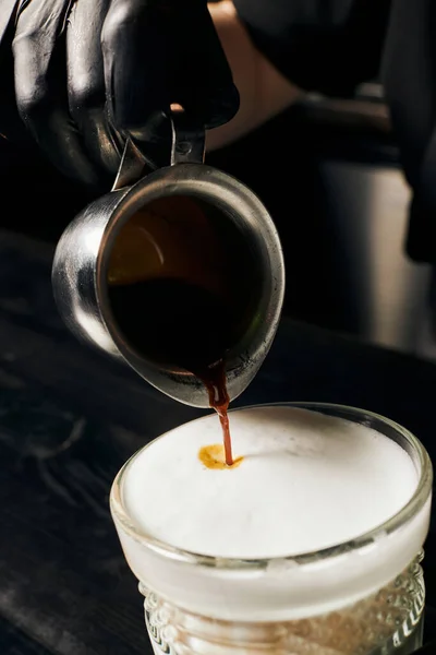 Barista in Latexhandschuhen bereitet Latte Macchiato zu, gießt Espresso, Kanne mit Kaffee, Makro — Stockfoto