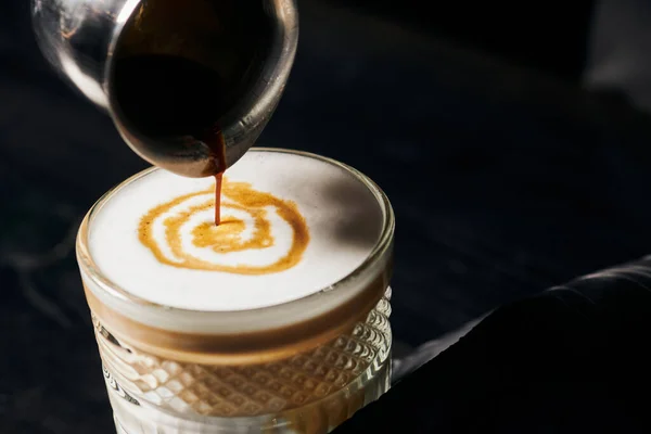 Latte macchiato, versando espresso in bicchiere, brocca con caffè, schiuma di latte, energia e caffeina — Foto stock