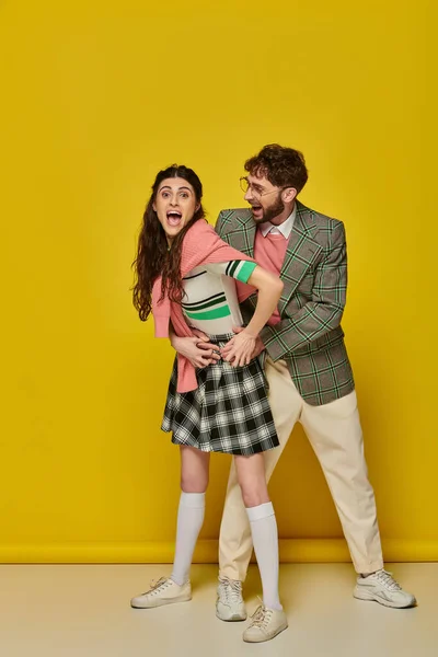 Alegre casal se divertindo, homem de óculos e mulher jovem com boca aberta, animado, roupas de estudante — Fotografia de Stock