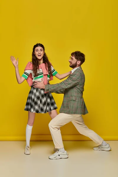 Junges Paar hat Spaß, Mann mit Brille umarmt junge Frau vor gelbem Hintergrund, Studenten, Outfits — Stockfoto
