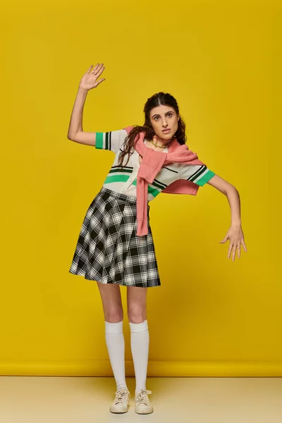 Brunette woman acting like a doll, gesturing unnaturally, standing on yellow backdrop, student — Stock Photo