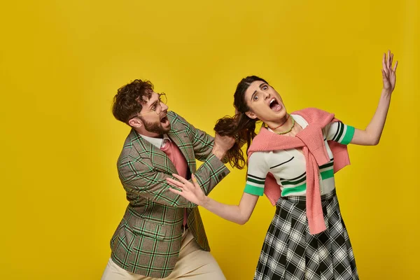 Bearded man pulling hair of scared woman on yellow background, conflict, physical, young couple — Stock Photo
