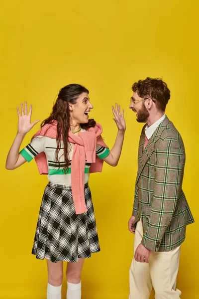 Femme excitée geste et regarder l'homme sur fond jaune, étudiants heureux, vêtements académiques — Photo de stock