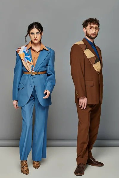 Pareja elegante, sesión de moda, hombre y mujer en trajes posando sobre fondo gris, marrón, azul, tendencias - foto de stock