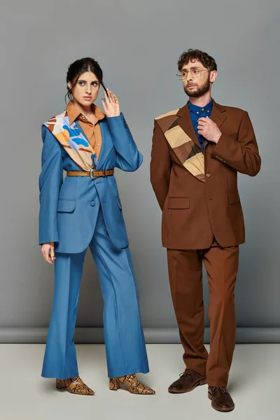 Homme et femme barbu en costumes sur mesure posant sur fond gris, brun, bleu, tournage de mode, couple — Photo de stock