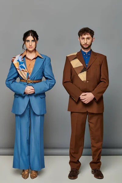 Bearded man and woman, tailored suits, posing on grey backdrop, brown, blue, fashion shoot, couple — Stock Photo