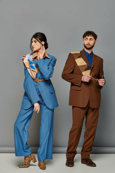 Homme et femme en costumes sur mesure, debout sur fond gris, tournage de mode, style corporatif, couple — Photo de stock