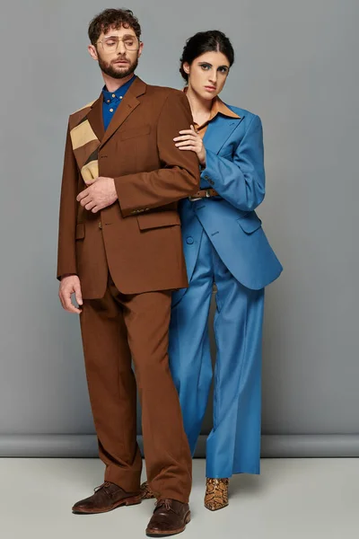 Anspruchsvoller Stil, Paar in maßgeschneiderten Anzügen, formeller Kleidung, grauem Hintergrund, Mann und Frau — Stockfoto