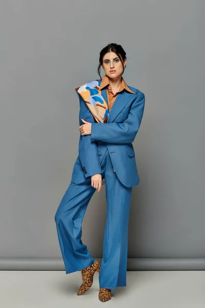 Femme brune avec un maquillage audacieux, modèle en costume bleu, tenue formelle, fond gris, style — Photo de stock