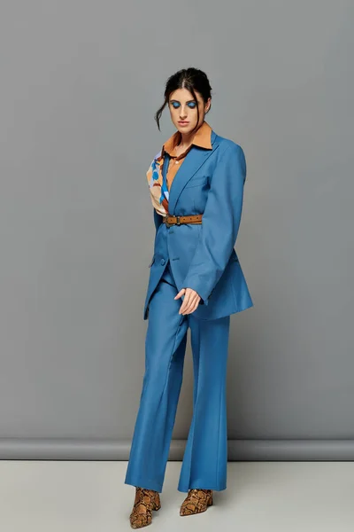 Hübsche Frau mit kühnem Make-up, Modell im blauen Maßanzug, formelle Kleidung, grauer Hintergrund, Stil — Stockfoto