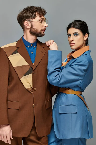 Modisches Paar, Models posieren in formeller Kleidung, blicken in die Kamera, grauer Hintergrund, elegante Anzüge — Stockfoto