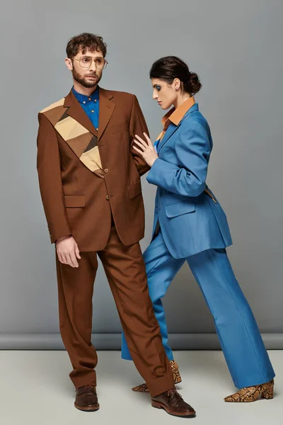 Модная поза, модели в формальной одежде на сером фоне, мужчина и женщина в костюмах, модная съемка — стоковое фото