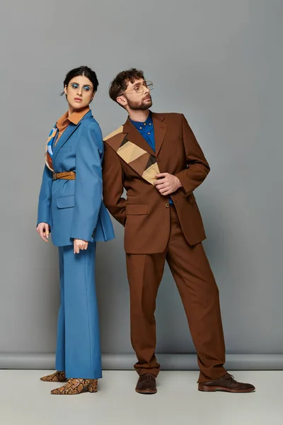 Модні моделі в костюмах позують на сірому фоні, чоловік і жінка в спеціальному формальному одязі, елегантно — стокове фото