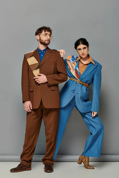 Modelos de moda em ternos posando em fundo cinza, homem e mulher elegantes em traje formal sob medida — Fotografia de Stock