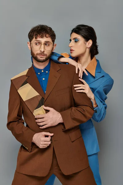 Hombre y mujer con estilo en trajes posando sobre fondo gris, estilo elegante, ropa formal, sofisticado - foto de stock