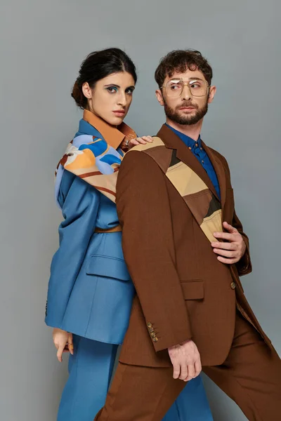 Стильна пара в костюмах позує на сірому фоні, елегантний стиль, сміливий макіяж, чоловік і жінка — стокове фото