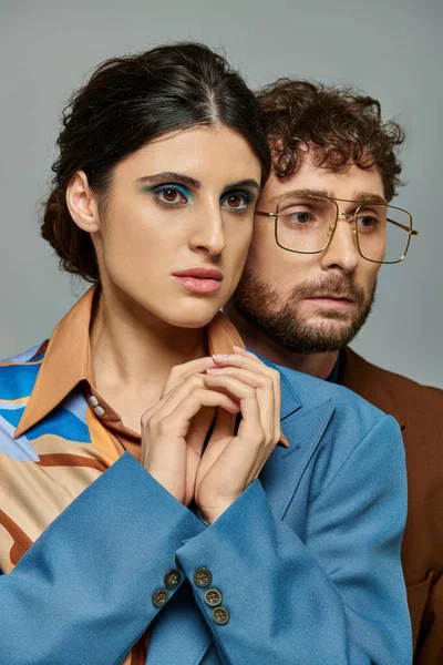 Retrato, casal na moda, fundo cinza, ternos, estilo elegante, mulher com maquiagem ousada, homem barbudo — Fotografia de Stock