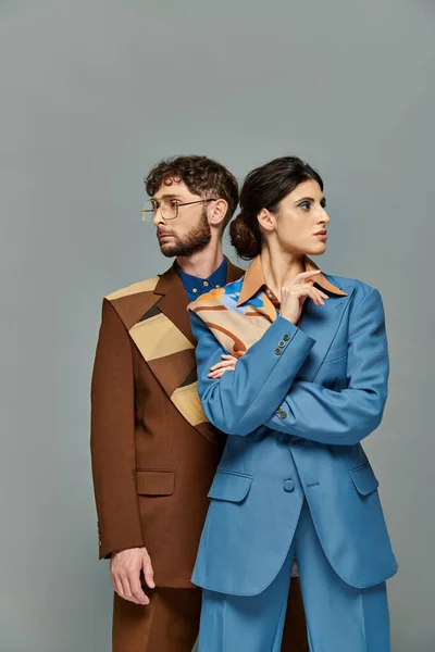 Porträt von Mann mit Brille und Frau, die in verschiedene Richtungen blicken, Models in trendigen Anzügen — Stockfoto