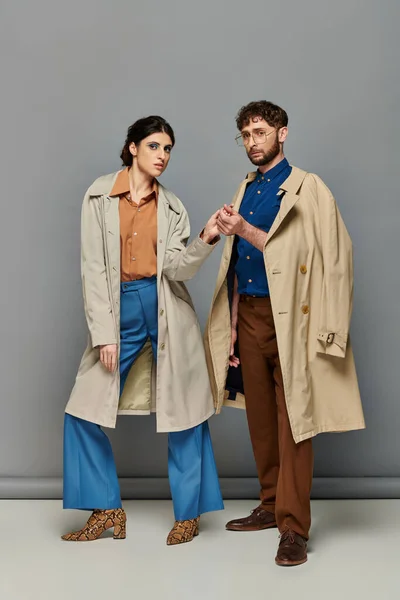 Romance, pareja en abrigos de trinchera, tiro de moda, hombre y mujer, ropa de abrigo, fondo gris, estilo - foto de stock