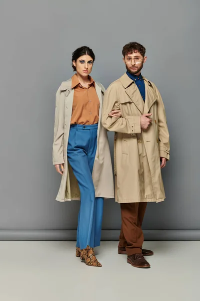 Stilvolles Paar in Trenchcoats, Modenschau, Mann und Frau, Oberbekleidung, grauer Hintergrund, Trends — Stockfoto