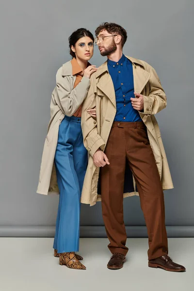 Outerwear, couple in trench coats, fashion shot, stylish man and woman, grey background, trends — Stock Photo