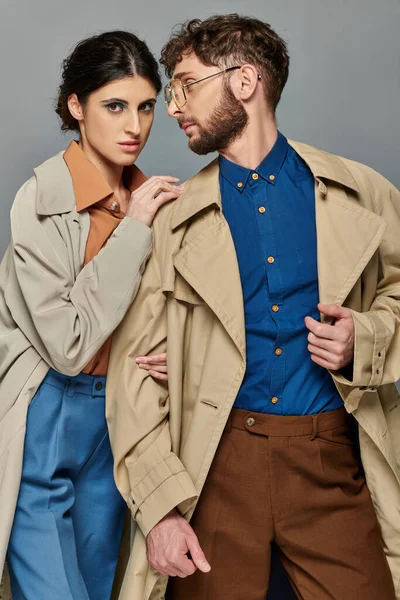 Ropa exterior, pareja en abrigos de trinchera, moda de otoño, hombre y mujer con estilo, fondo gris, otoño - foto de stock