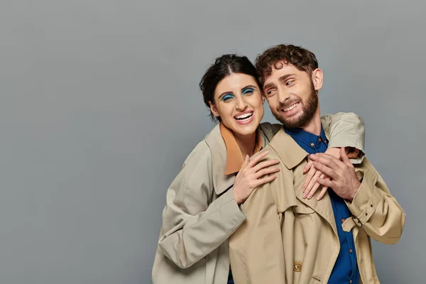Temporada de outono, sorriso, casal romântico abraçando no fundo cinza, casacos de trincheira, estilo, romance — Fotografia de Stock