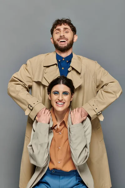 Positives Paar, Oberbekleidung, Herbstsaison, grauer Hintergrund, Mann und Frau in Trenchcoats, Stil — Stockfoto