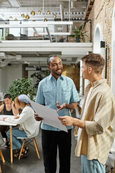 Happy african american man pointing at project and looking at colleague, startup, generation z — Stock Photo