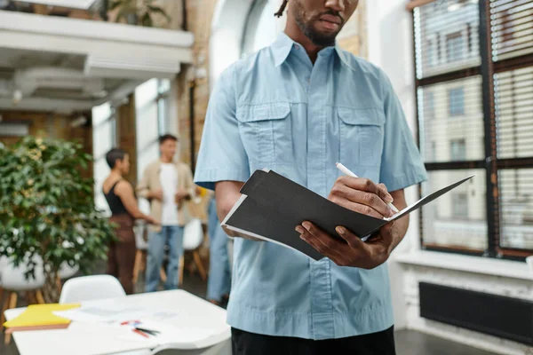 Cropped view of african american man taking notes, holding folder, writing down ideas, creative — Stock Photo