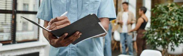 Cropped view of african american man taking notes, holding folder, writing down ideas, banner — Stock Photo