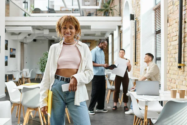 Positive african american woman with braces holding smartphone, folder, startup, gen z, coworking — Stock Photo