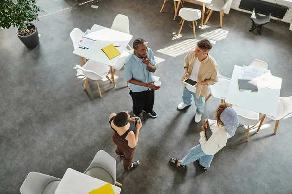 Gente de negocios interracial feliz de pie en círculo, discutiendo el proyecto de inicio, la celebración de gadgets - foto de stock