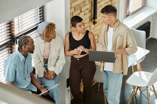Personas interraciales escuchando a colega con laptop, compartiendo ideas, coworking, startup, negocio - foto de stock