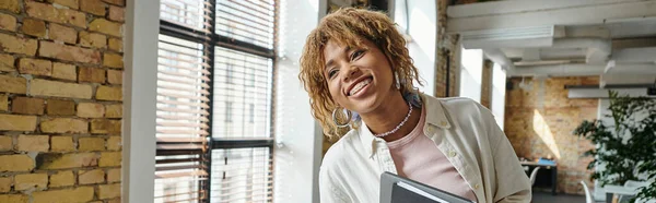 Positive african american woman with braces smiling, holding folders in open space, startup, banner — Stock Photo