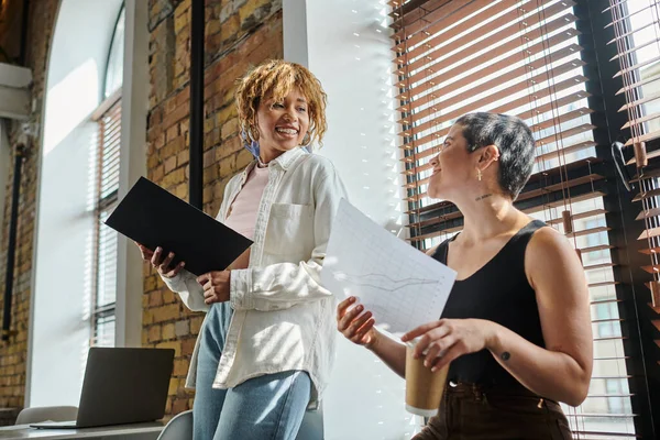 Happy interracial women discussing project, startup, graphs, black woman with folder, gen z — Stock Photo