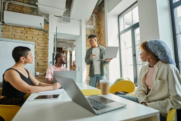 Young man discussing startup project with african american team leader, colleagues, coworking — Stock Photo