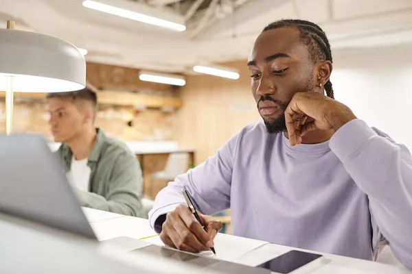 Focused african american man using laptop, writing down ideas, creativity, brainstorm, startup — Stock Photo
