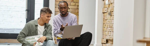 Afrikanisch-amerikanischer Mann zeigt männlichen Kollegen Projekt auf Laptop, sitzt auf Treppe, Start-up, Banner — Stockfoto